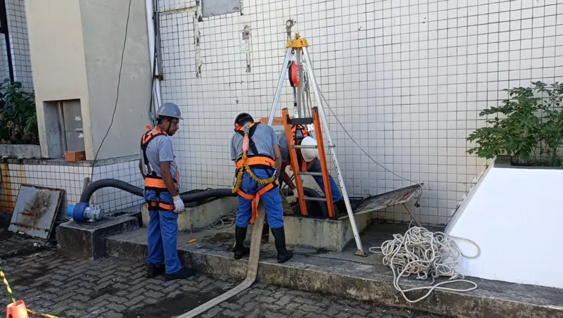 Equipe da Essencial Saúde Ambiental com tripé e cinto de segurança na limpeza de uma cisterna